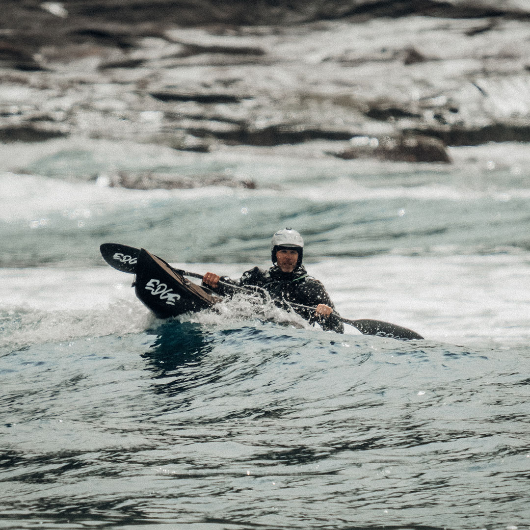 Mann i kajakk surfer på bølger